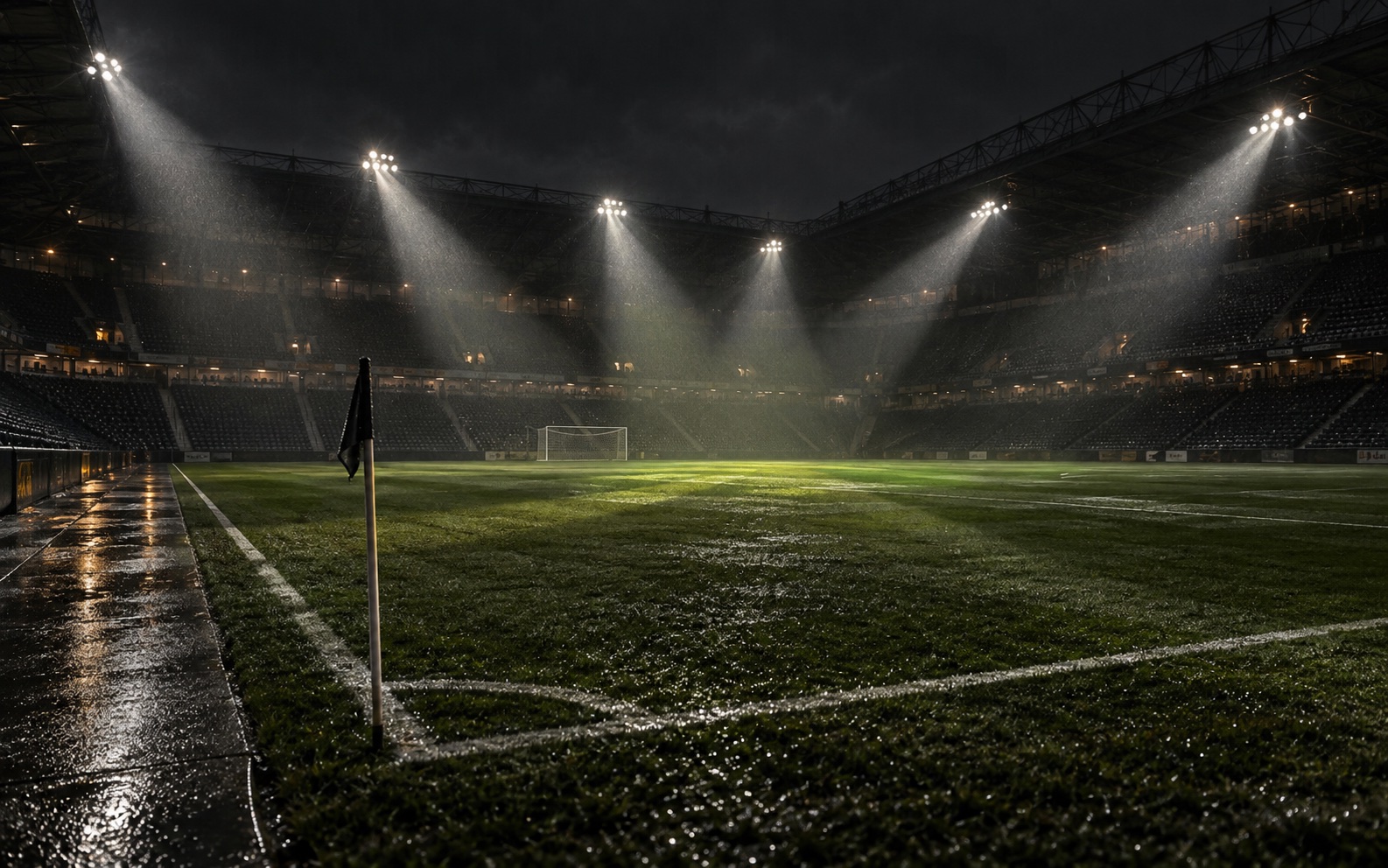 Five stadium floodlights converge across an empty rain-dark pitch